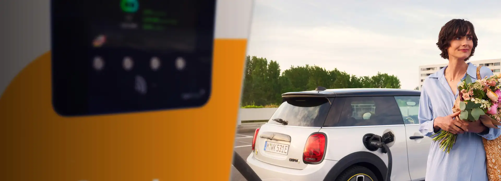 Frau auf Parkplatz lädt E-Auto nach Einkauf