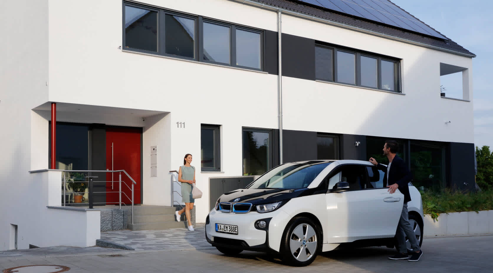 Paar steigt in i3 vor Haus mit einer EnBW-Solaranlage ein