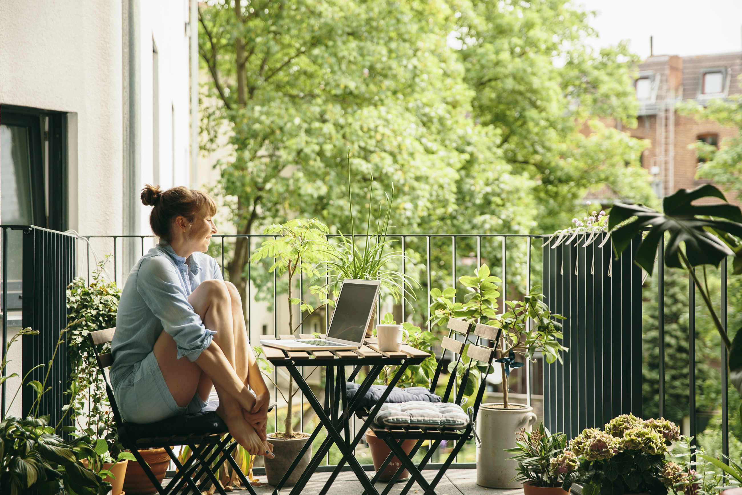 Frau mit Laptop auf Balkon