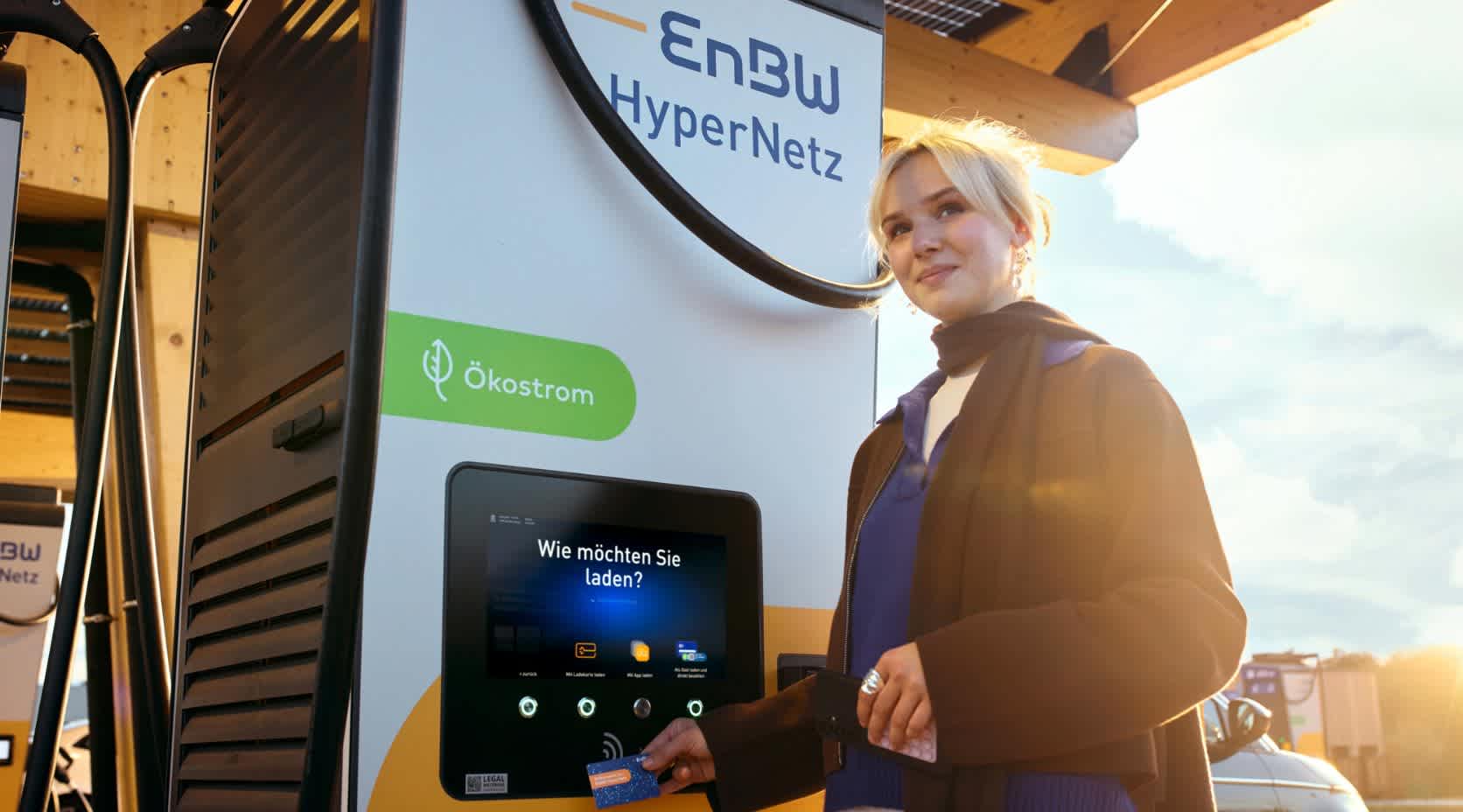 Junge Frau bedient eine Ladesäule in einem Ladepark