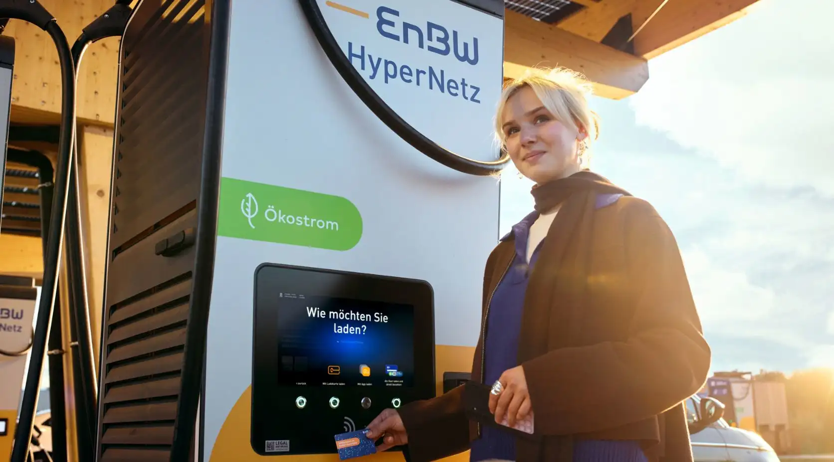 Junge Frau bedient eine Ladesäule in einem Ladepark