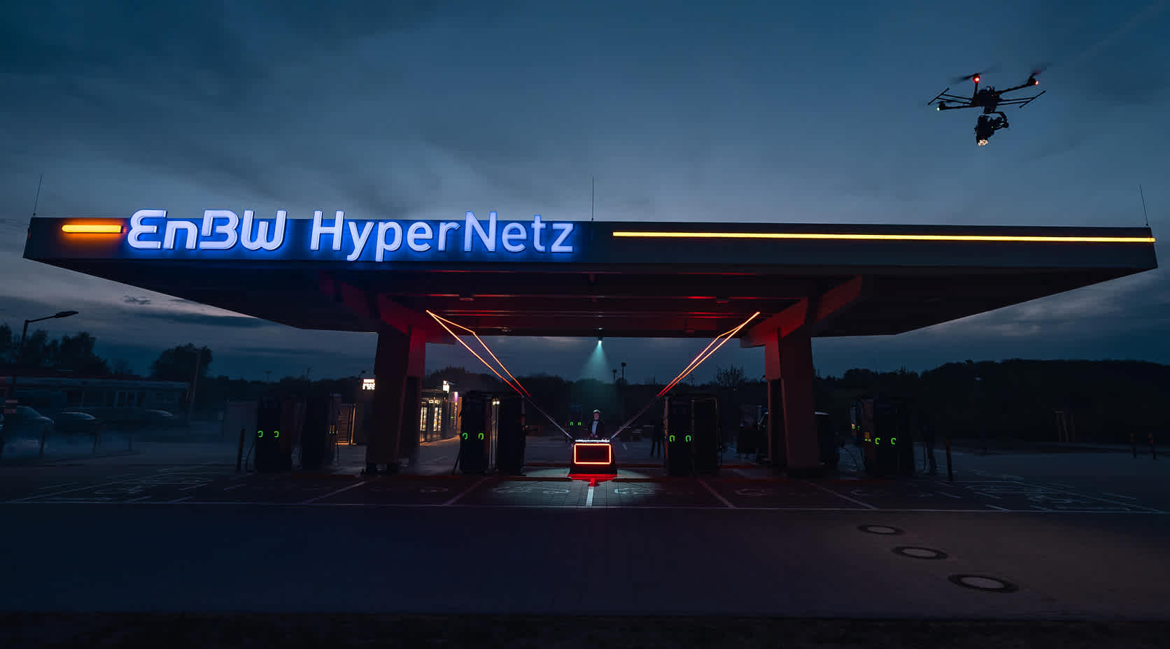 Beleuchteter EnBW HyperNetz nachhaltiger Ladepark im Dunkeln.