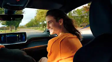 Frau fährt auf dem Beifahrersitz eines E-Autos