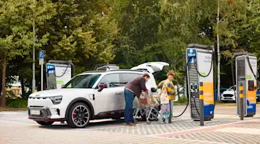 Familie lädt ihr Auto auf einem Supermarktparkplatz