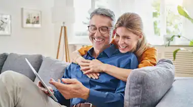 Mann und Frau auf der Couch mit einem Tablett.