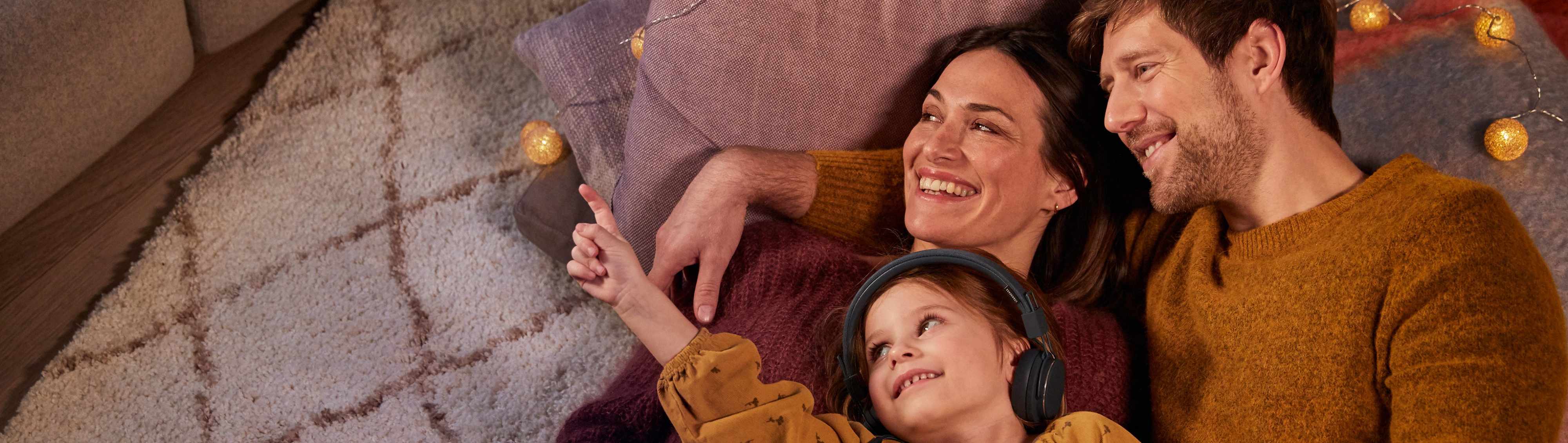 Familie liegt entspannt auf dem Boden.