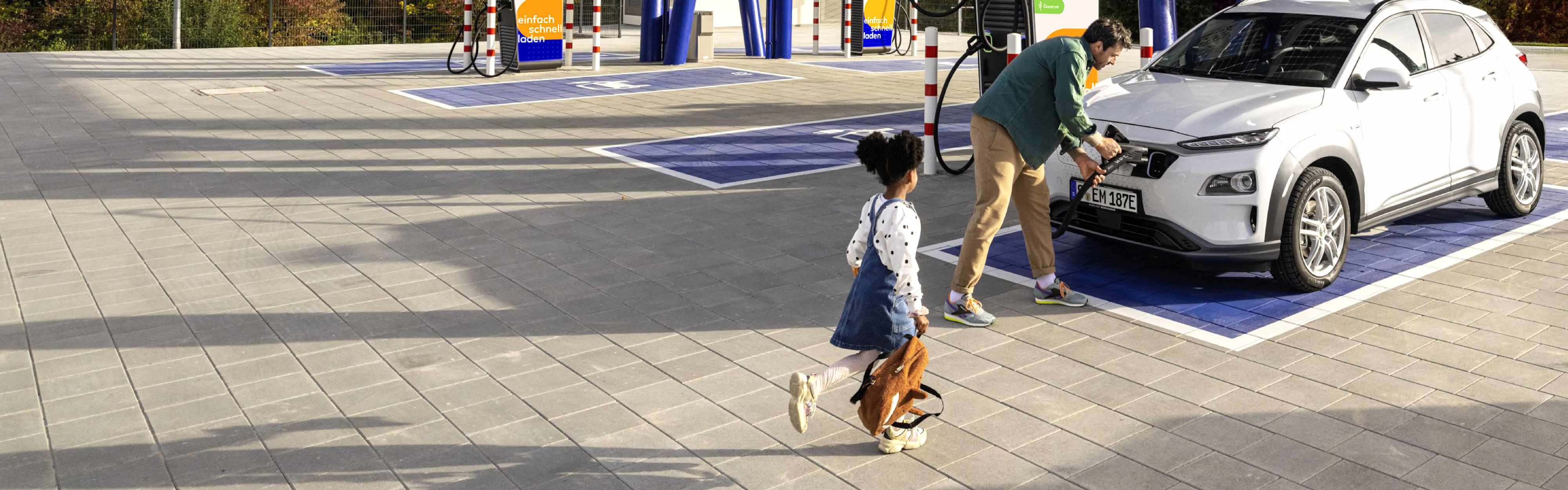 Vater lädt E-Auto in EnBW Ladepark