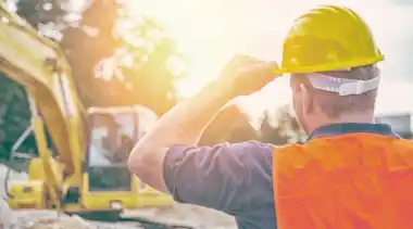 Ein Bauarbeiter steht vor einem Bagger