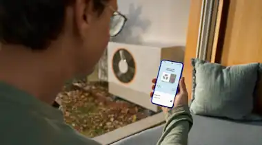 Ein Mann betrachtet sein Smartphone, auf dem ein Screen zur Steuerung einer Wärmepumpe angezeigt wird.