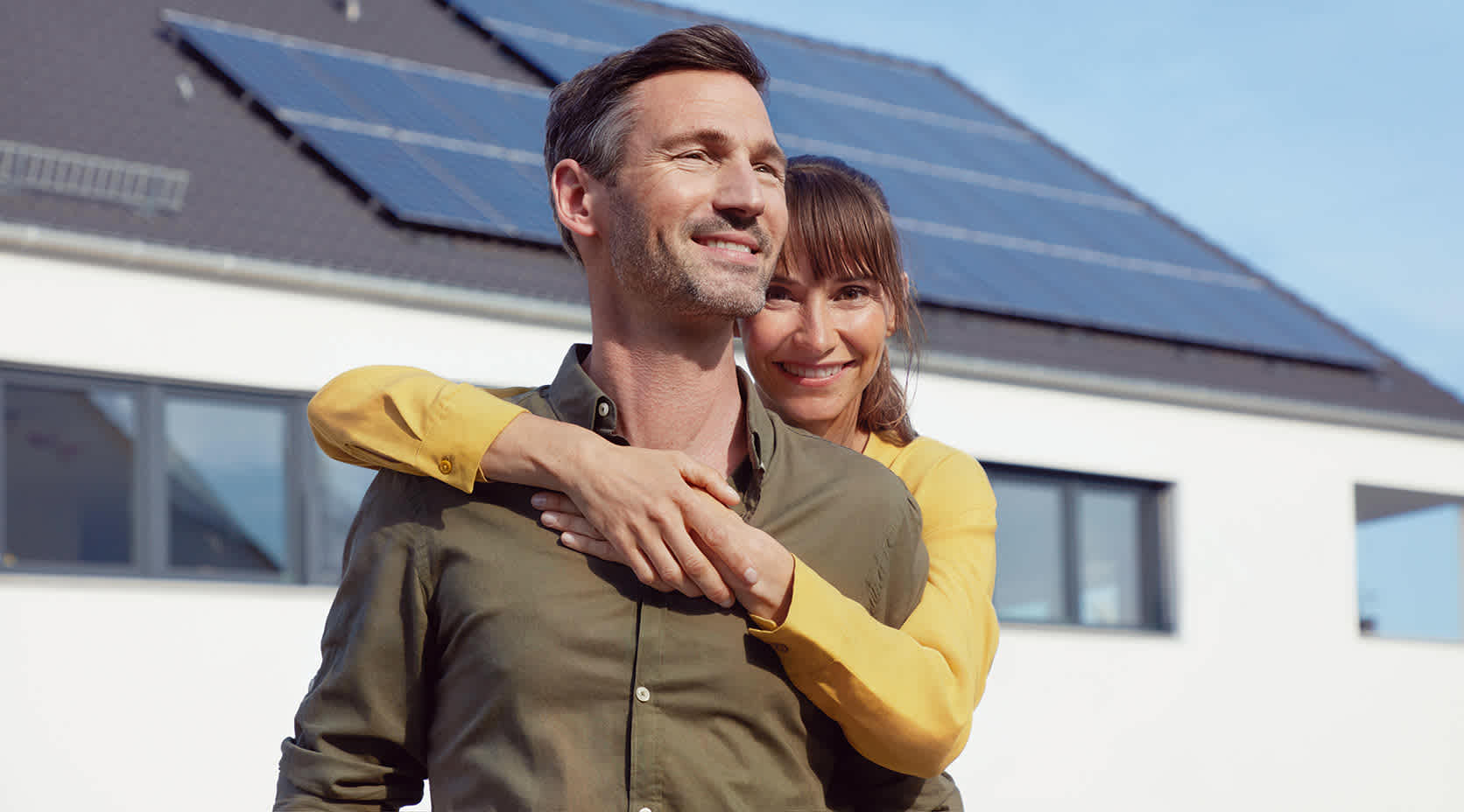 EnBW Kunde Daniel mit seiner Frau, im Hintergrund sein Haus mit EnBW solar+ Solaranlage