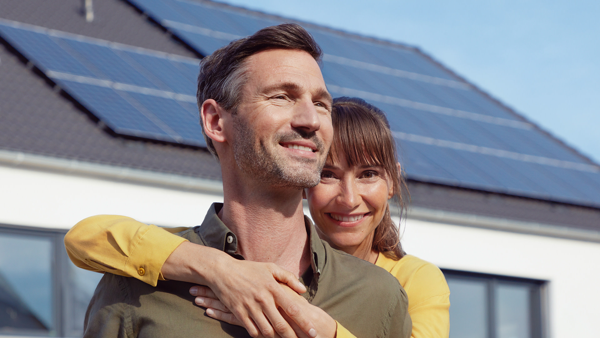 EnBW Kunde Daniel mit seiner Frau, im Hintergrund sein Haus mit EnBW solar+ Solaranlage