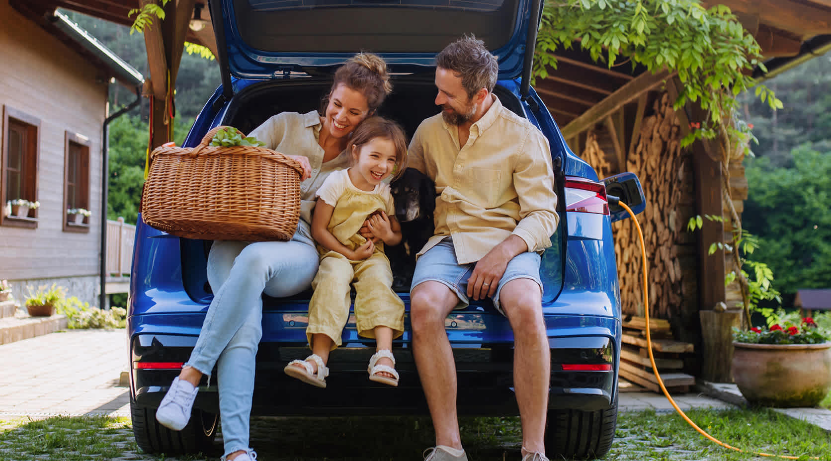 EnBW Familie sitzt freudig im Kofferraum eines Autos