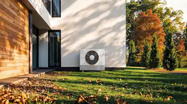 Wärmepumpe vor einem Haus im Herbst