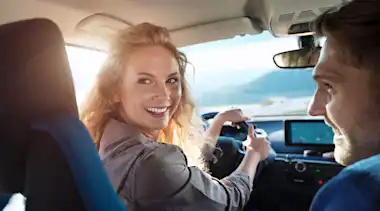 Junges Paar ist gut gelaunt im E-Auto unterwegs