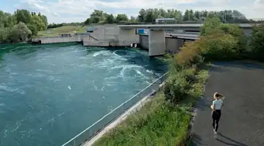Joggerin läuft an einem Wasserkraftwerk vorbei