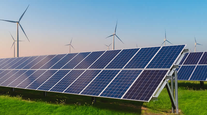 PV-Anlagen auf Wiese. Windräder im Hintergrund