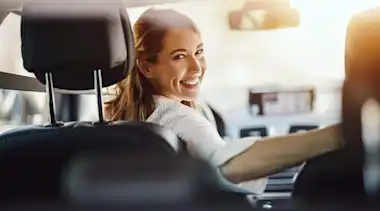 Eine lachende Frau in ihrem E-Auto