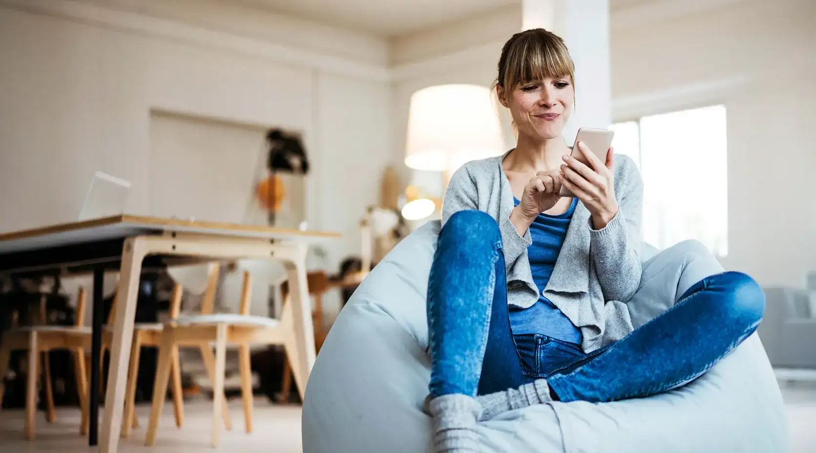 Frau sitzt mit ihrem Smartphone auf einem Sitzsack