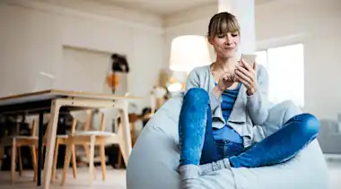 Frau sitzt mit ihrem Smartphone auf einem Sitzsack