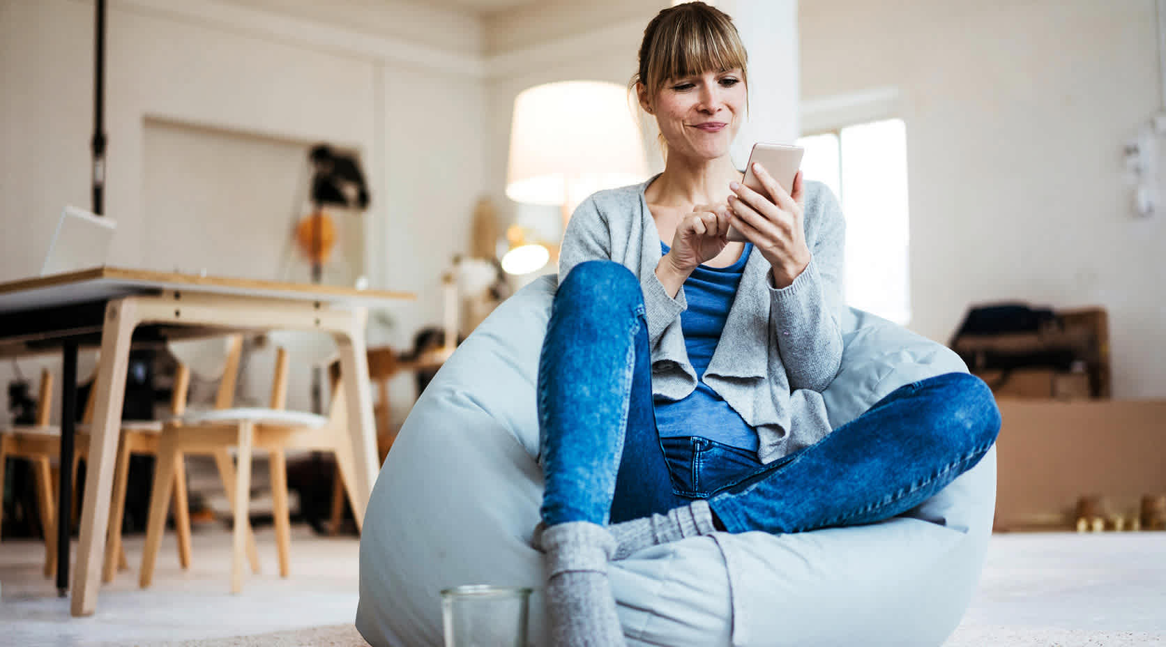 Frau sitzt mit ihrem Smartphone auf einem Sitzsack