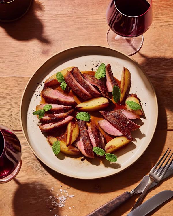 Seared Duck Breast with Roasted Apples and Ojai Mountain 2023 Syrah Seared duck breast sliced on a plate with roasted apples and black pepper gastrique, paired with Ojai Mountain 2023 Syrah