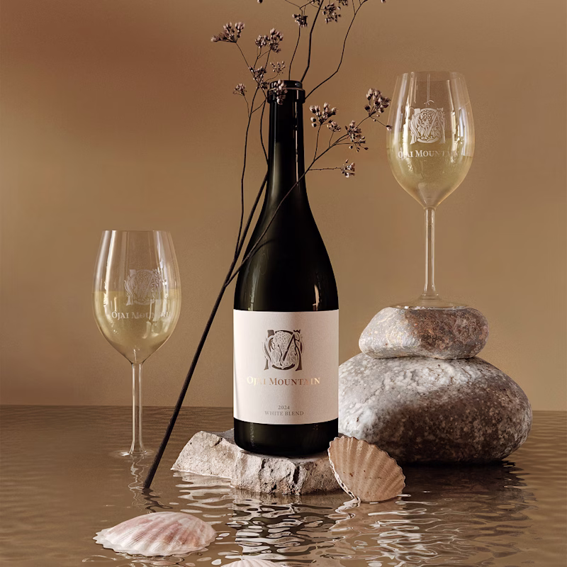 Ojai Mountain 2024 White Blend with poured glasses, smooth stones and shells