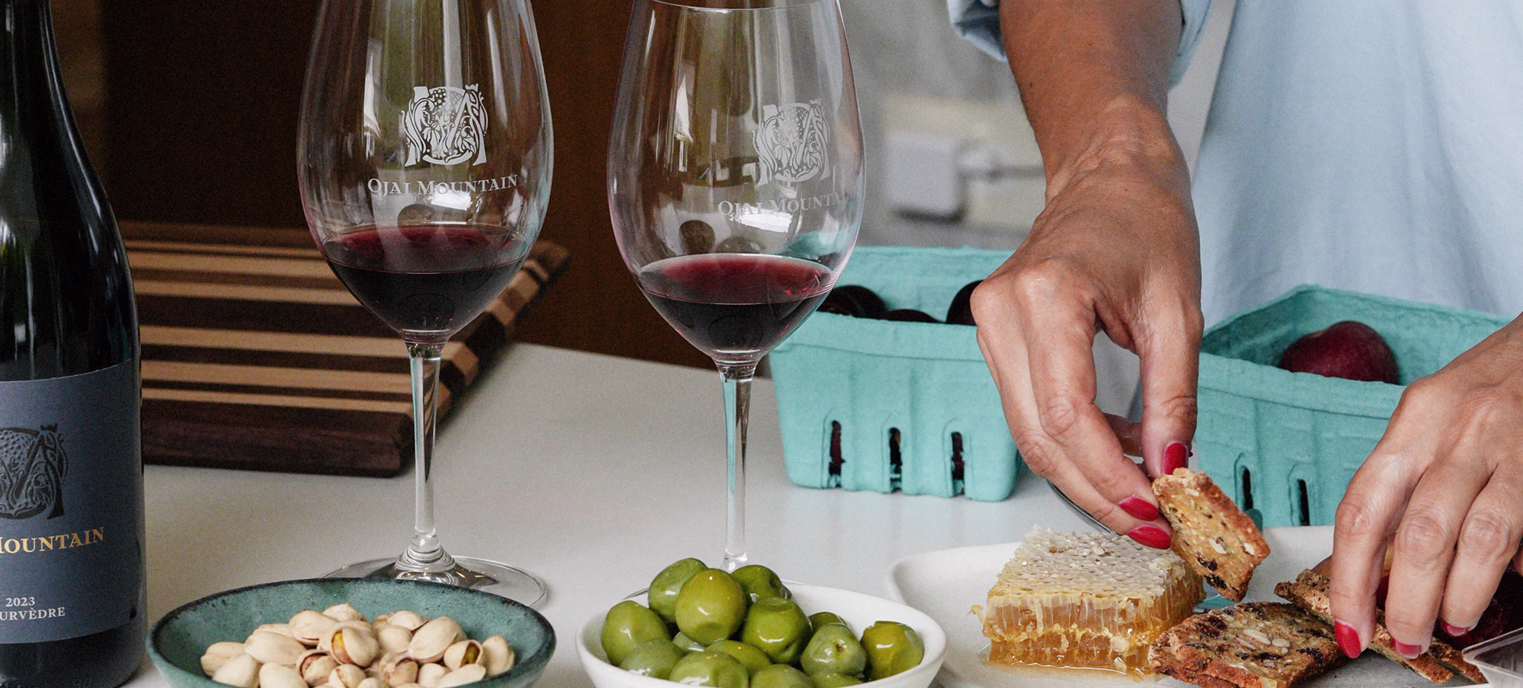 Ojai Mountain bottle and glasses on a table with olives and berries