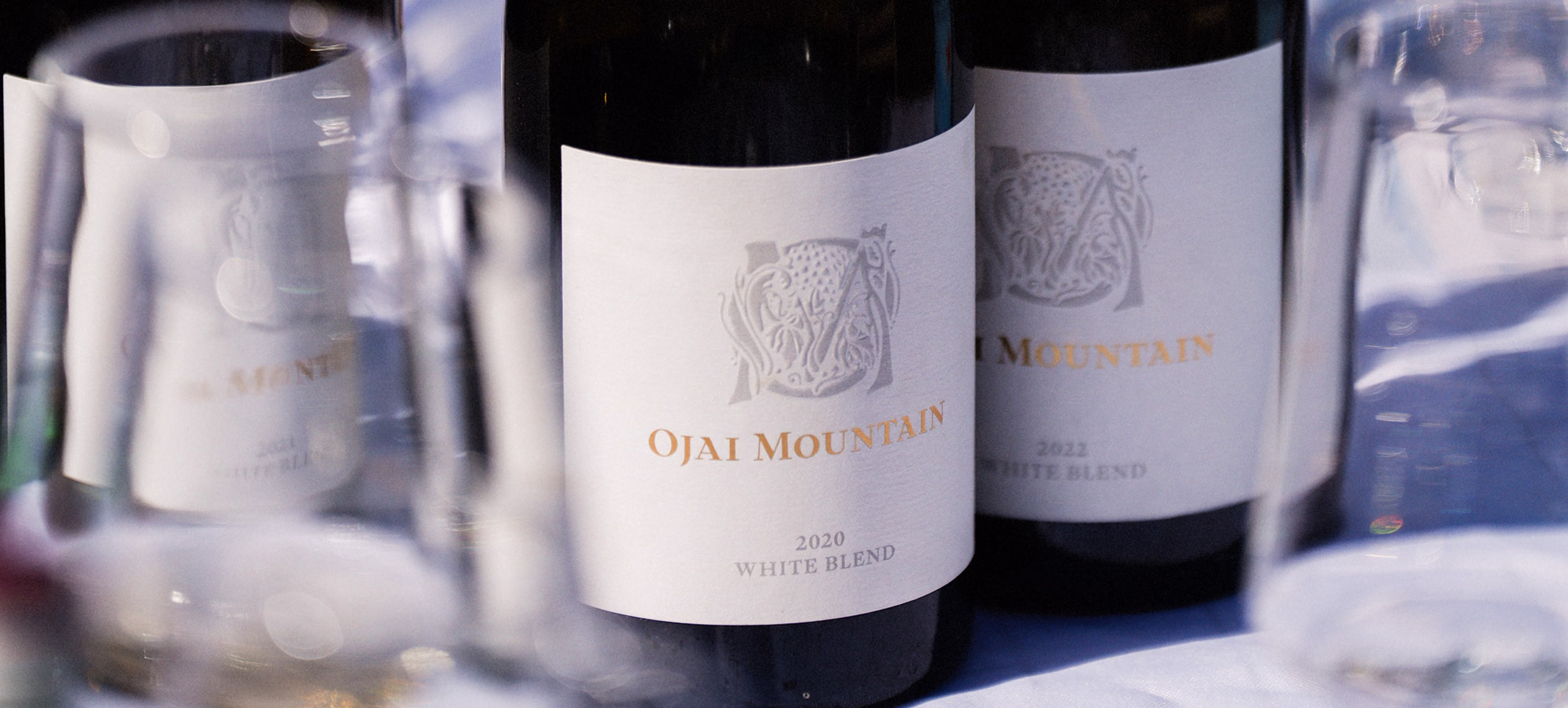 Three Ojai Mountain 2020 White Blend bottles with tasting glasses behind
