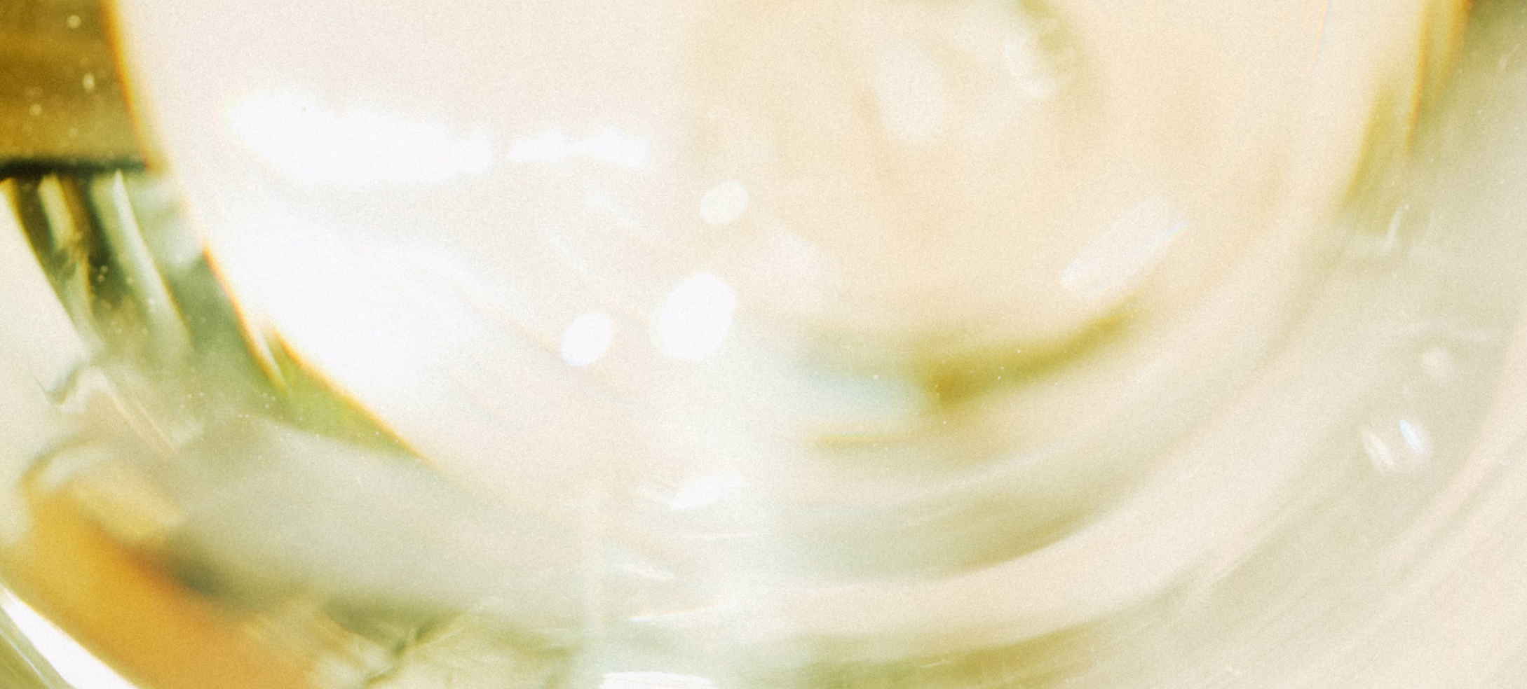 2025 White Wine in the Glass Close-up of white wine curving inside a glass, lit warm and pale gold