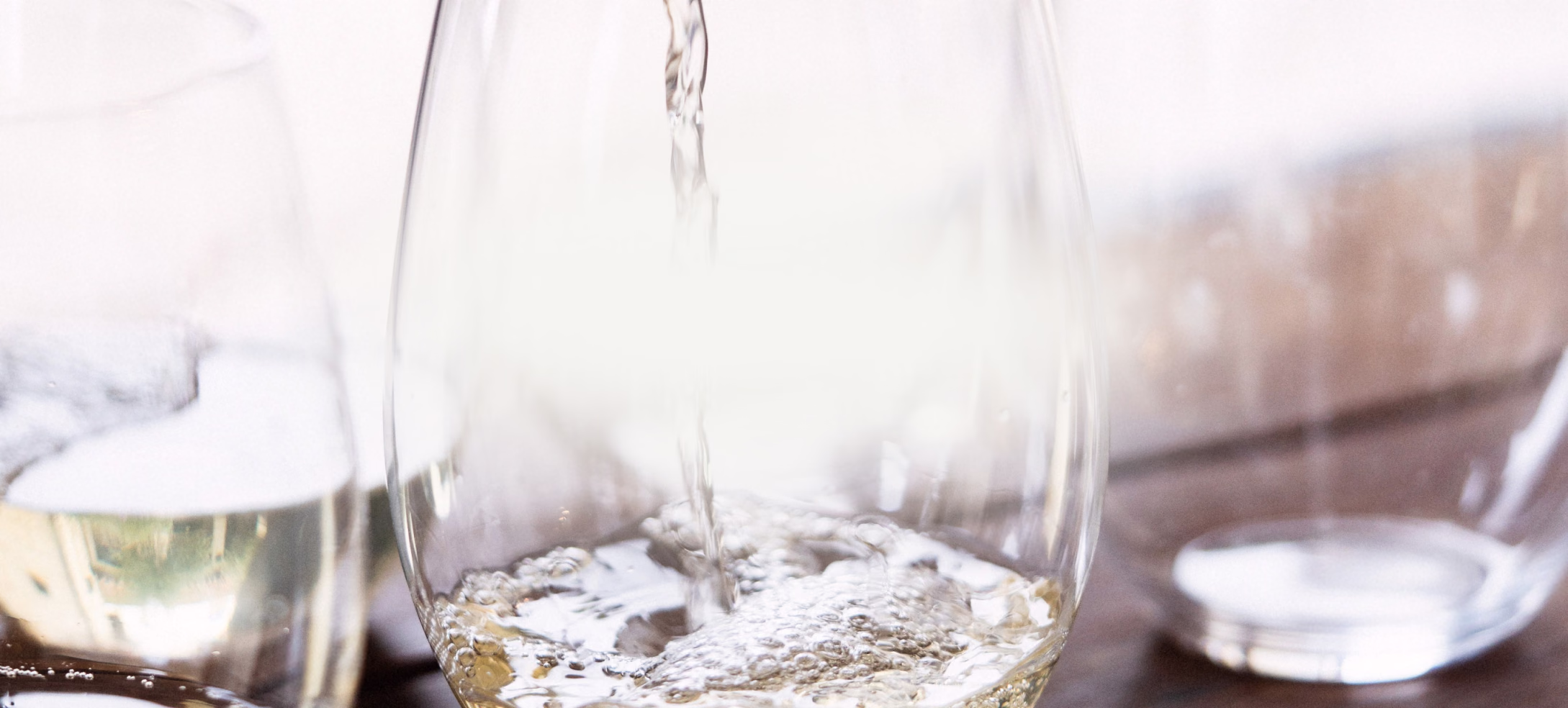 White wine being poured into a tasting glass in bright light