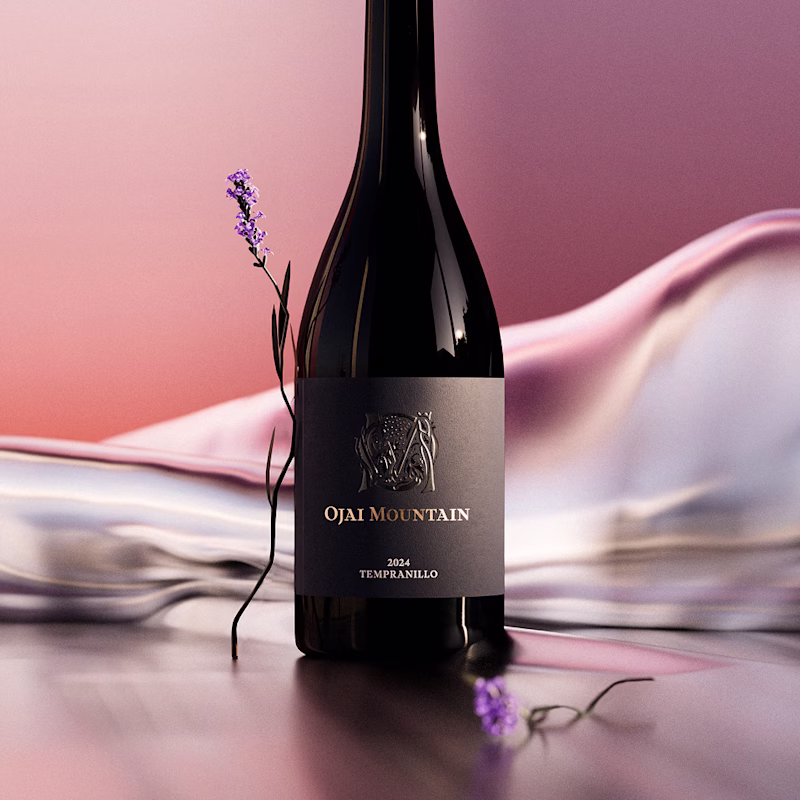 Ojai Mountain 2024 Tempranillo bottle on pink silk with a sprig of lavender