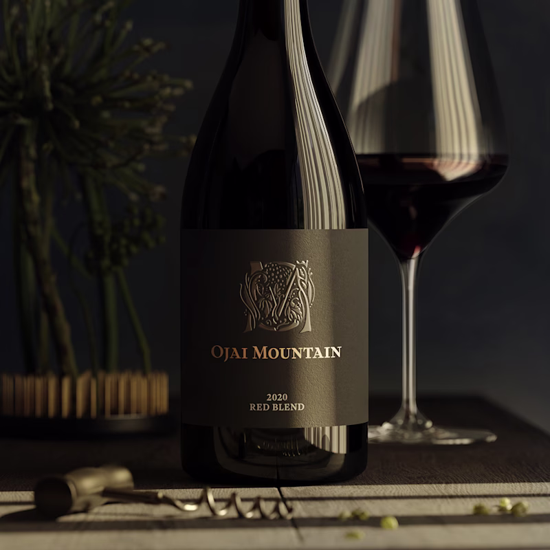 Ojai Mountain 2020 Red Blend bottle beside a poured glass in low light