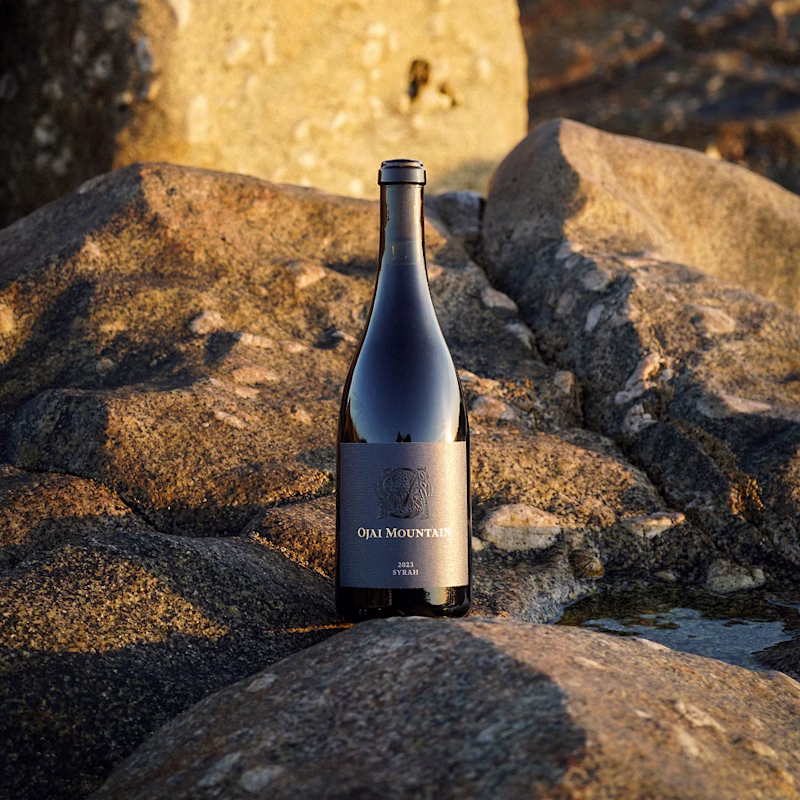 Ojai Mountain 2023 Syrah bottle set among sunlit boulders