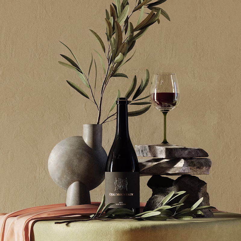 Ojai Mountain 2022 Red Blend styled with olive branches and a poured glass Ojai Mountain 2022 Red Blend styled with olive branches and a poured glass