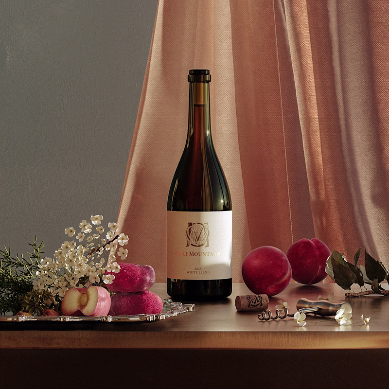 2025 Estate White in Peach Drapery Ojai Mountain 2025 Estate White bottle before peach drapery with plums and silver tray