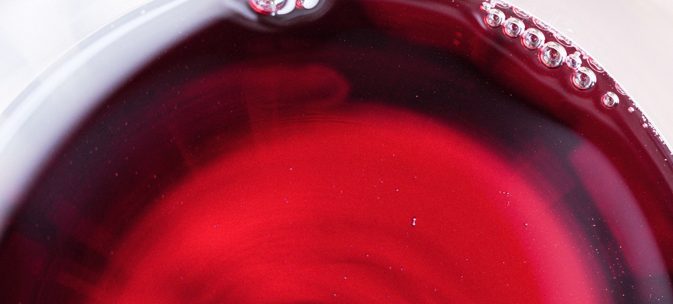 Close view of red wine surface with bubbles at the glass rim