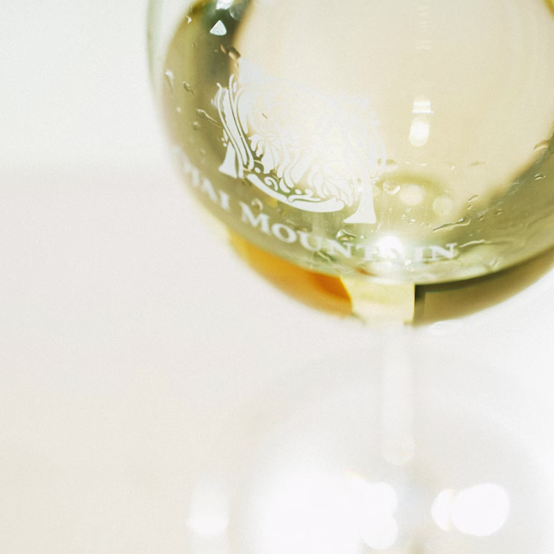 Estate White Poured at the Table Glass of Ojai Mountain Estate White beside bottle and savory tart in low light