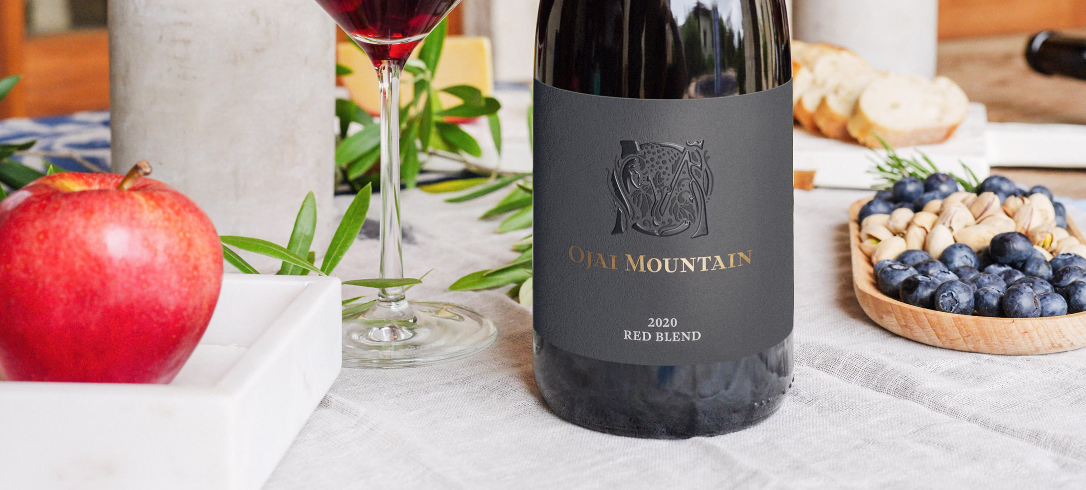 Ojai Mountain 2020 Red Blend on a table with pomegranate and berries