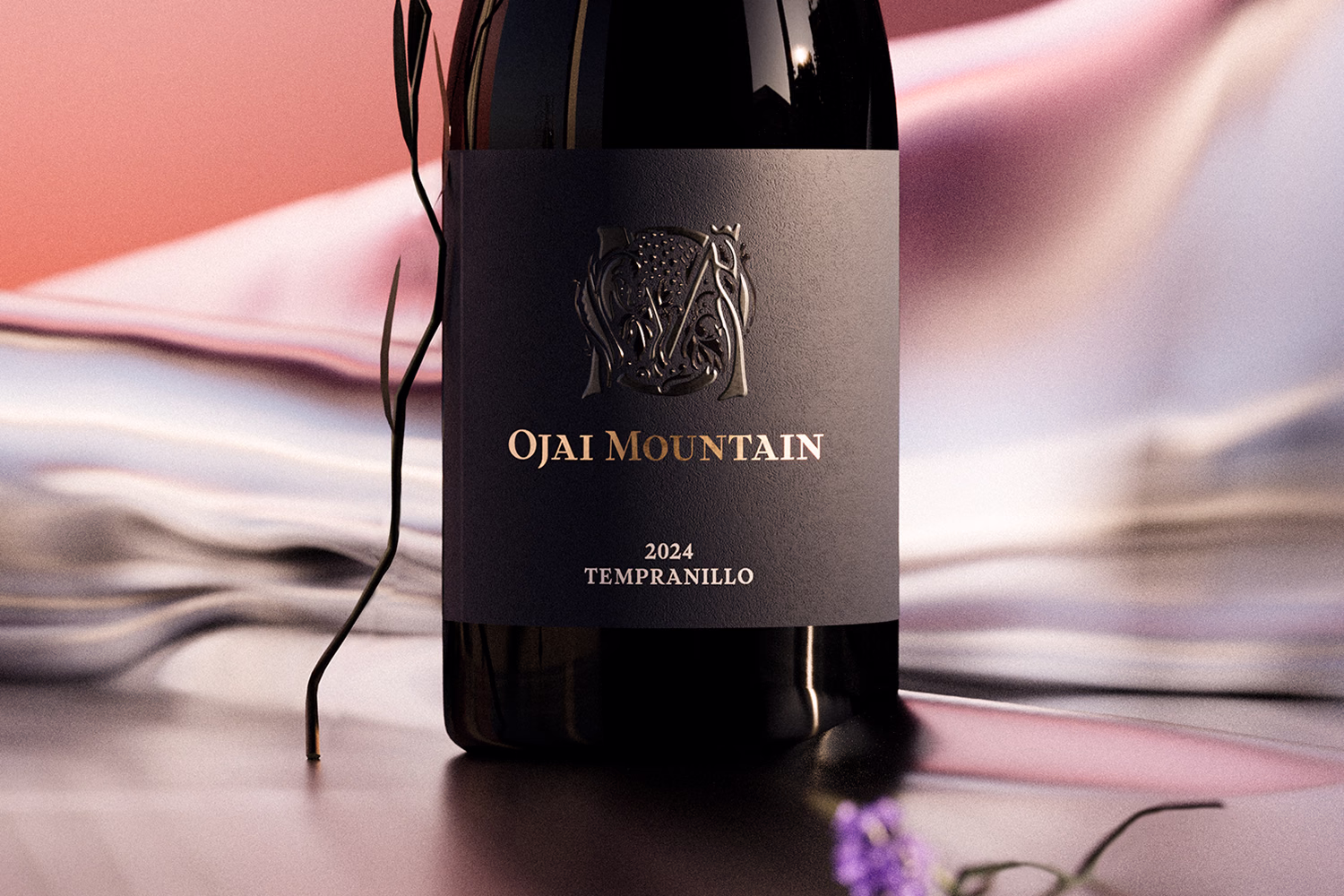 Ojai Mountain 2024 Tempranillo bottle close-up on an iridescent surface with a purple flower