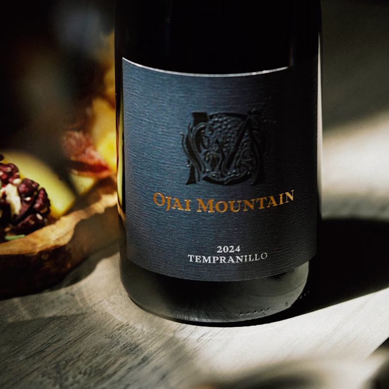 Ojai Mountain 2024 Tempranillo bottle in warm light behind a soft blurred foreground