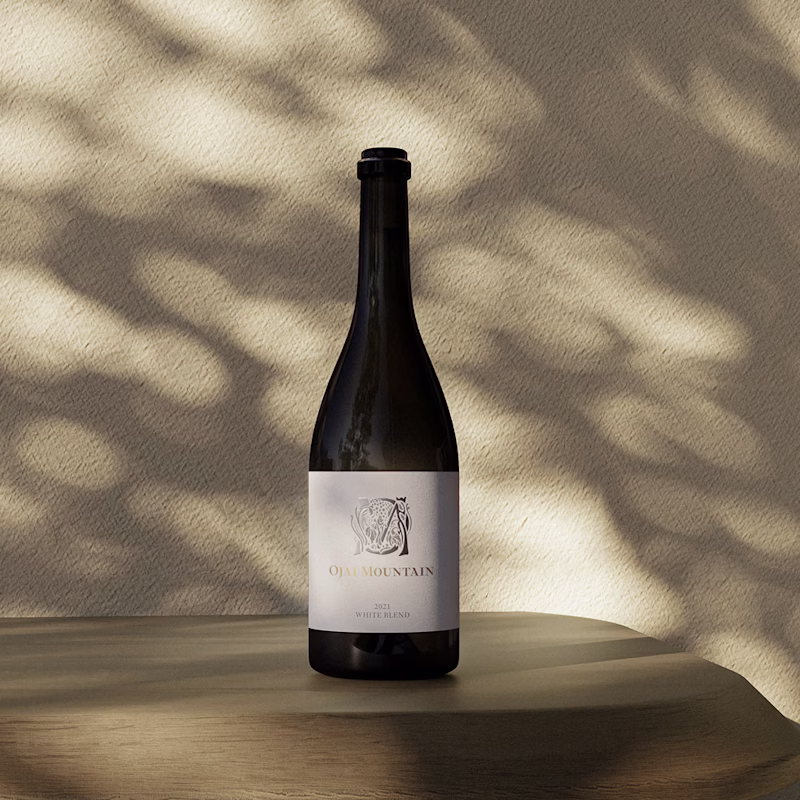 Ojai Mountain 2021 White Blend bottle in dappled sunlight on warm sand Ojai Mountain 2021 White Blend bottle in dappled sunlight on warm sand