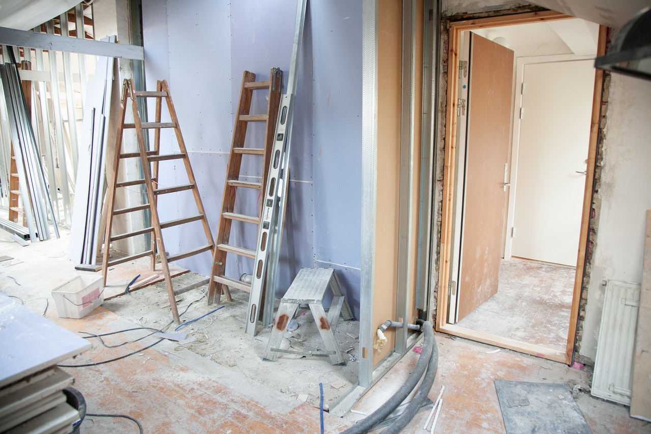 A house in the middle of renovation, wooden ladders lean against wall and tools lie on the floor