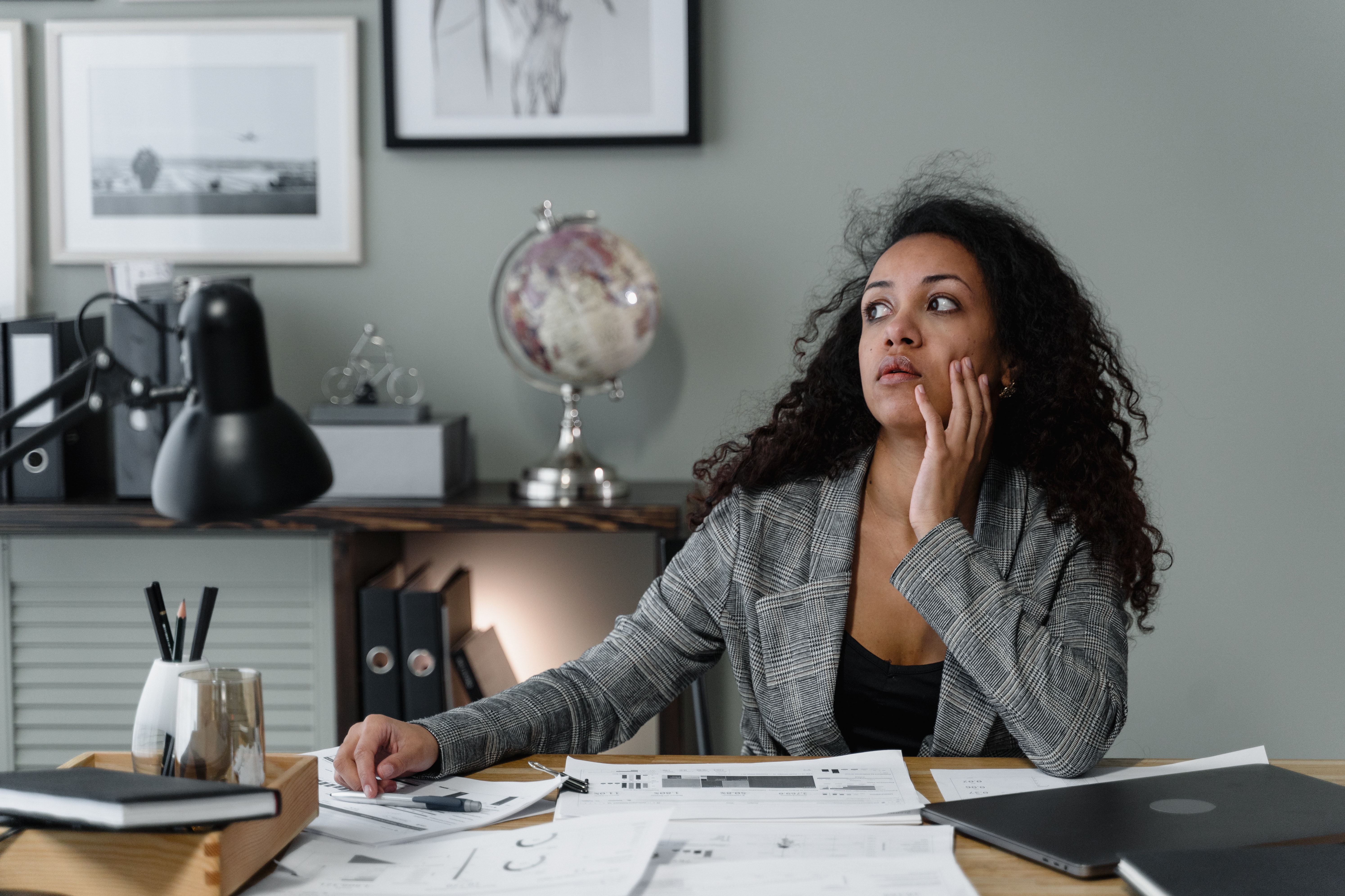 Young woman sitting at a desk with papers and thinking about taxes.