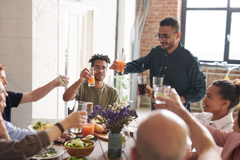 group of young flatmates toast each other over large dining table
