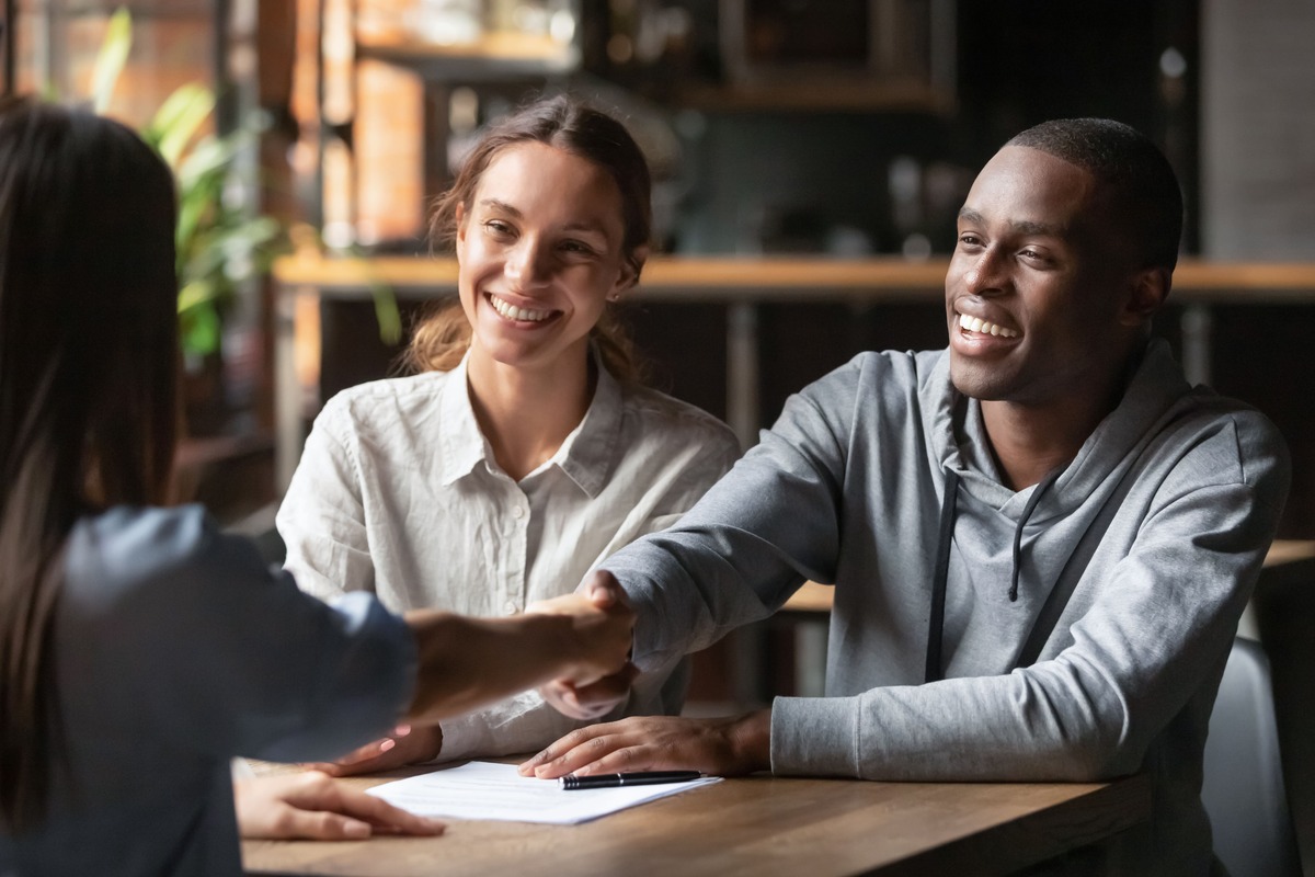 A man and a woman smiling and shaking hands with a solicitor.