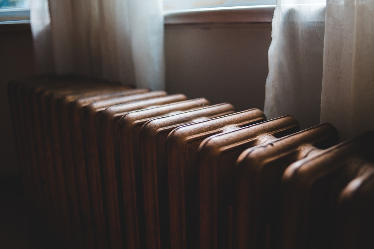 Old radiator next to a window sill.