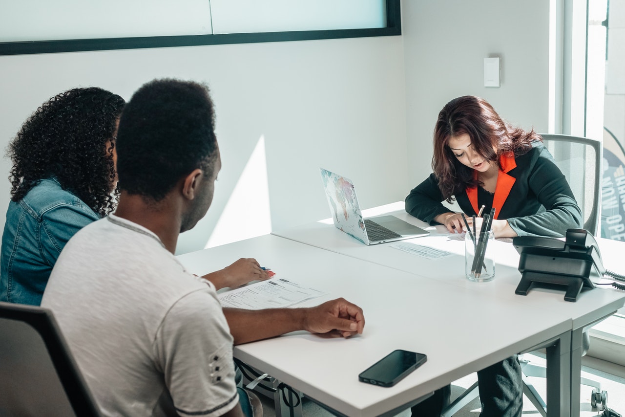 A couple sat across a table from a solicitor in an office