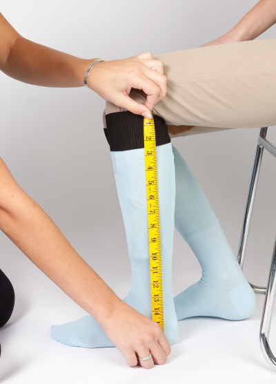 A rider sitting down having their leg measured for height using tape from the knee to heel.