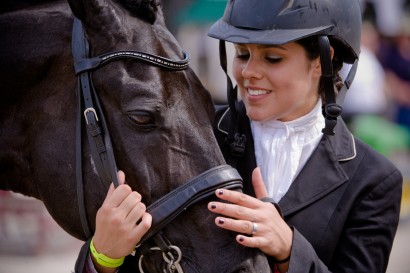 dressage rider petting her horse's face at a show