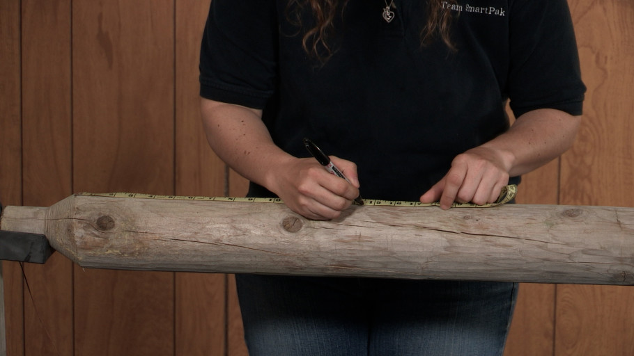 A person measuring and marking sections on a ground pole.